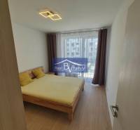 Bedroom with wood-patterned flooring in a 2-room apartment, double bed and curtains.