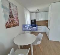 A kitchen in a 2-room apartment with a wooden decor floor and a dining table.