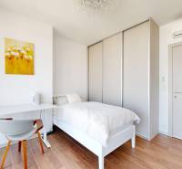 A bright room with a bed, a desk, and a wooden decor floor in a 3-room apartment.