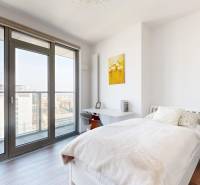 A bright bedroom in a 3-room apartment with a bed, a desk, and a view of the city.