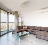 Living room in a 3-room apartment with large windows, a sofa, and a glass table.