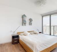 Bedroom in a 3-room apartment with wood-patterned flooring, large windows, and artistic decor.