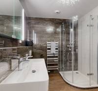 Bathroom with an illuminated mirror, shower corner, and wooden decor flooring in a 3-room apartment.