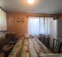 Dining room with a large table, refrigerator, and curtains, floor with wood decor.