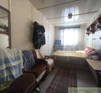 A room with a sofa, bed, and window, part of a cabin, cozy interior.