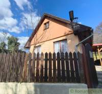 A cottage in Hronská Dúbrava with a wooden fence and a blue sky.
