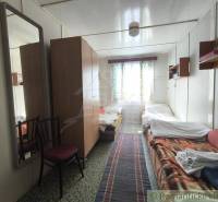 The interior of a cabin with two beds, a narrow carpet, and wooden cabinets.