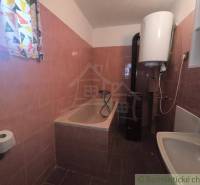 A bathroom in a cabin with a bathtub, sink, and electric boiler.