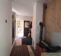 A hallway in a cottage with a wooden decor floor and a wood-burning stove.