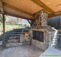 A covered outdoor fireplace with a stone chimney in a cabin in Hronská Dúbrava.