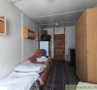 A cozy room in a cabin with a bed, a wardrobe, and shelves on the wall.