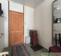 The interior of a cabin with wooden doors, an older television, and a stove on a floor with carpets.