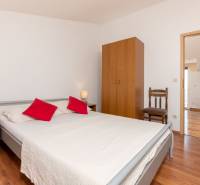 Interior of a holiday apartment with a wood-patterned floor, a bed, and simple furniture.