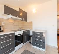 A kitchen in a holiday apartment with dark gray cabinets and tiled flooring.