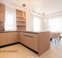 A kitchen in a family house with an island, modern lighting, and a wooden decor floor.
