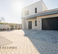 A family house in Gyor-Moson-Sopron with a garage and a paved courtyard, surrounded by greenery.