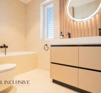 Bathroom in a family house with a bathtub, mirror, and window, wooden decor.