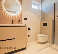 Bathroom in a family house with a round mirror, shower, and toilet.
