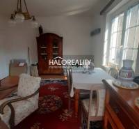 A traditionally furnished living room in a family house with a red carpet and wooden furniture.