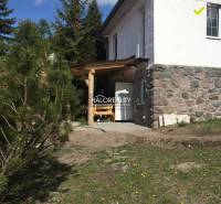 A family house in Turček with a stone foundation and a wooden shelter in the garden.