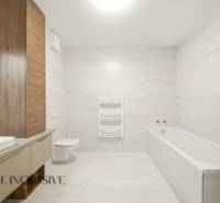 A bathroom with a bathtub and wooden decor in a 2-room apartment, simple lines and light walls.