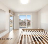 A bright bedroom with wood-patterned flooring and a view in a two-room apartment.