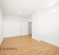 A spacious room in commercial premises with a wooden decor floor, white walls.