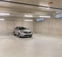 Underground parking lot with a car, concrete walls, and lighting in the garages.