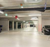 Parking garage with cars and a motorcycle, underground lighting, the space gives a clean impression.