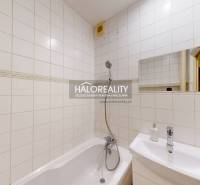 Bathroom with white tiles, a bathtub, and a sink in a 2-room apartment.