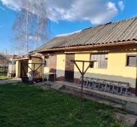 A family house in the village of Holiare with a lawn, trees, and a wooden shelter.