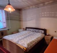 Bedroom in a family house with a bed and curtains by the window.