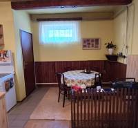 Kitchen and dining area in a family house with wooden elements and a curtain.