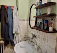 Bathroom with a sink in a family house, with wooden shelves on the wall.