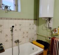 A bathroom in a family house with a bathtub, tiles, and a boiler.