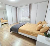 A bright bedroom in a three-room apartment with a large built-in wardrobe and a floor with a wooden decor.
