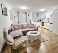 Living room in a 3-room apartment with a corner sofa, television, and wooden decor flooring.