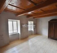 The interior of a cabin with a wooden ceiling, a floor with a wooden decor, and a wardrobe.
