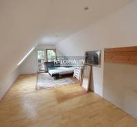 Attic room in a cottage with a bed, mirror, and floor with wooden decor.
