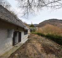 A cottage in Hodruša - Hámre with steep terrain and a view of forested hills.
