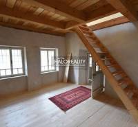 Interior of a cabin with a wooden staircase, a floor with a wooden decor, and a carpet.
