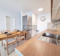 Kitchen in a 2-room apartment with a wooden table, sink, and cooking equipment.