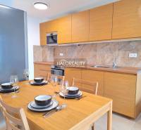 A kitchen in a 2-room apartment with wooden decor, built-in appliances, and marble cladding.