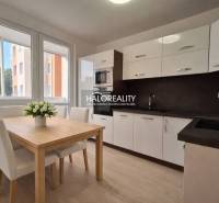 A kitchen in a 3-room apartment with a wooden decor floor and a dining table.