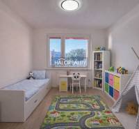 A children's room with a colorful carpet, white furniture, and a wooden decor floor.