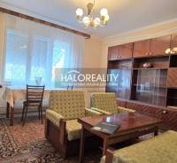 Living room in a family house with a wooden decor floor, a large couch, and shelves.