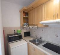 Kitchen corner in a studio apartment with a microwave and wooden cabinets.