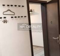 The hallway in a 3-room apartment with a wooden decor floor and wall hooks.