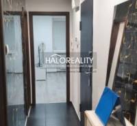 A narrow hallway in a 3-room apartment with black floor tiles and a wall mirror.