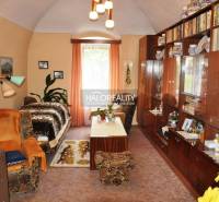 Living room with antique furniture, shelves, and books. Next to it is the entrance to the family house.